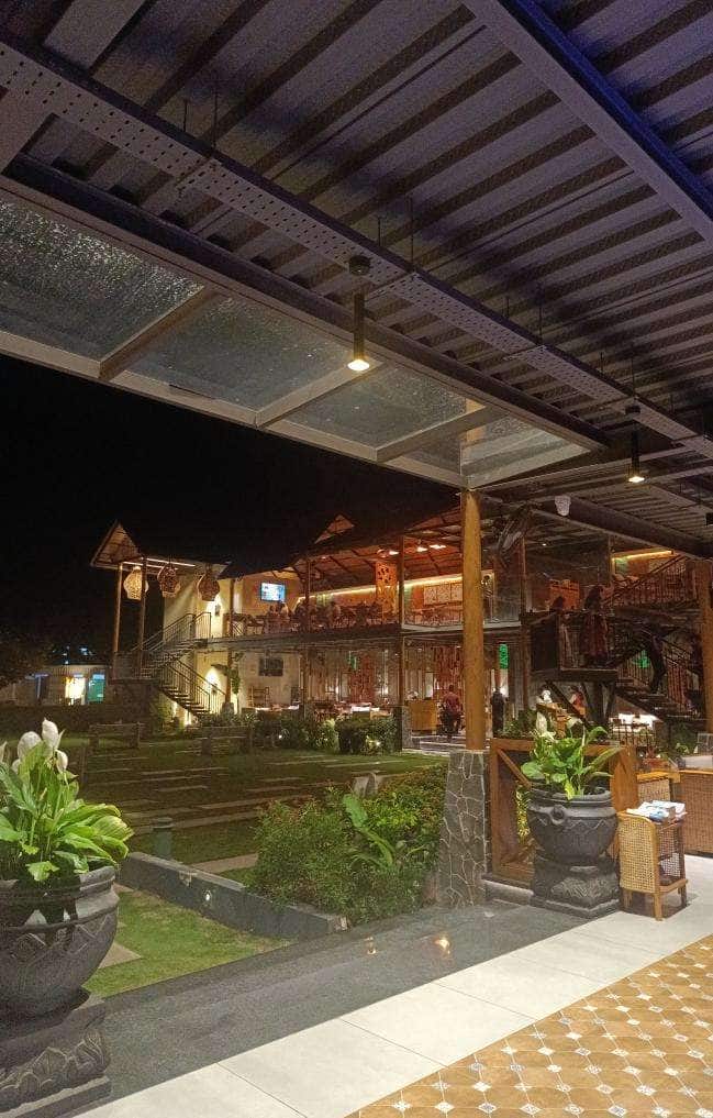 Glass and wood pavilions illuminated at night with tropical plants