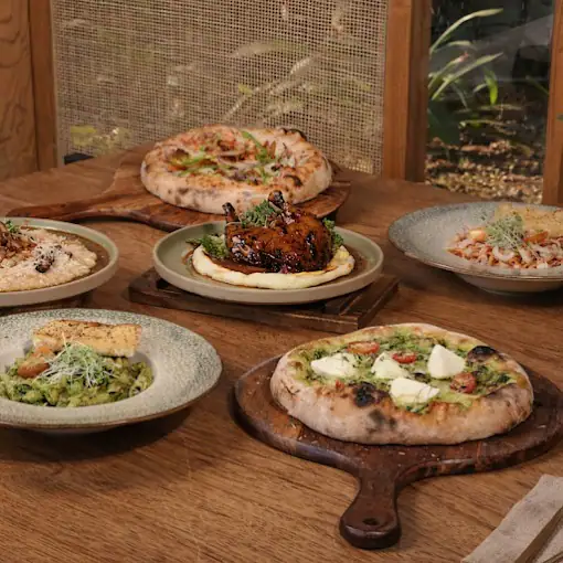 Gourmet spread of artisanal pizzas, pesto burrata, pasta and confit chicken